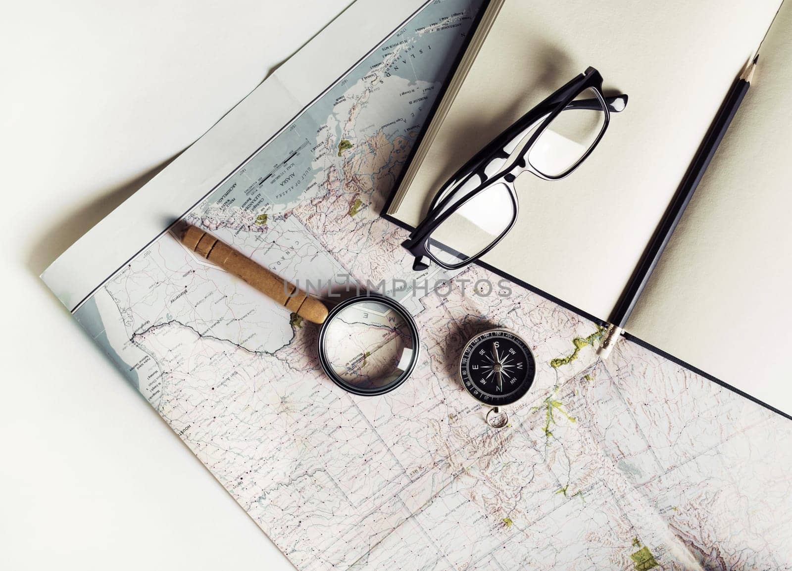 Stationery, travel accessories and vacation items. Vintage toned image. Flat lay. Top view. Map, notebook, magnifier, compass glasses and pencil