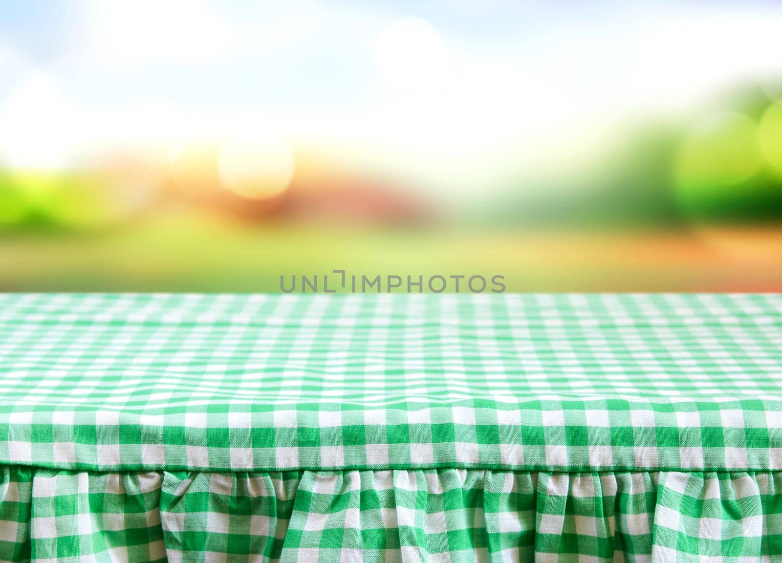 Checkered gingham picnic tablecloth blurred nature background.Empty space food advertisement template.