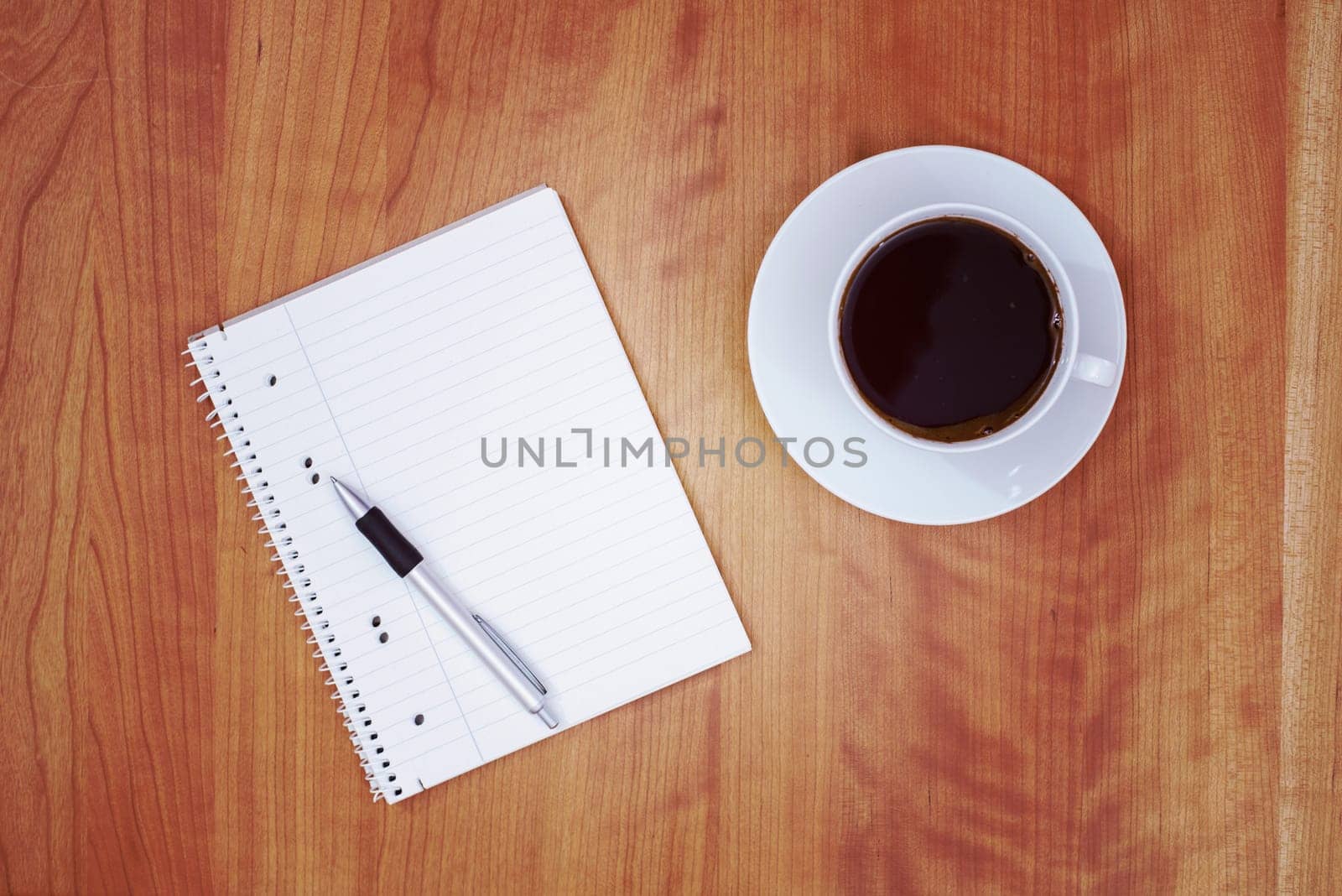notepad with pen and a cup of tea on wooden table from above