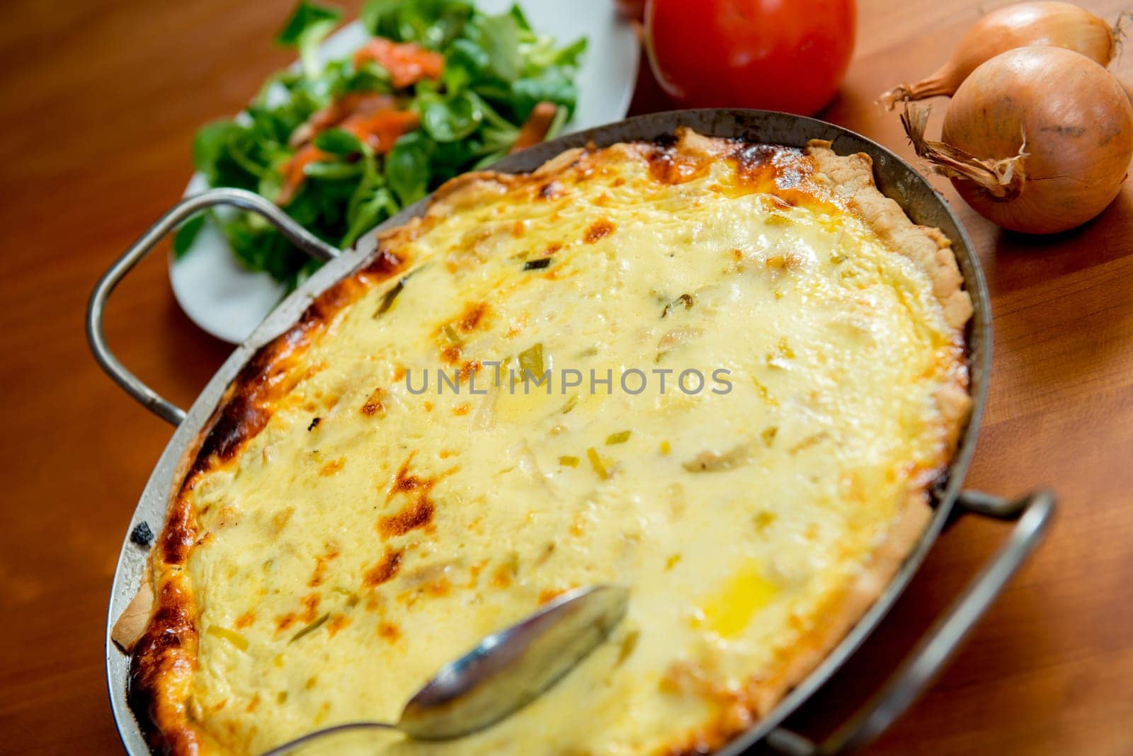 baked quiche with field salad on wooden table