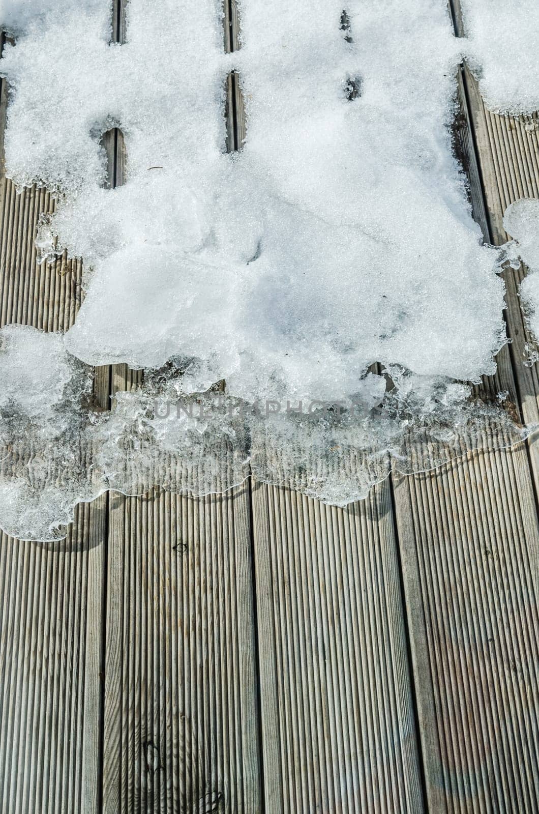 Melting snow on a wooden terrace, close-up