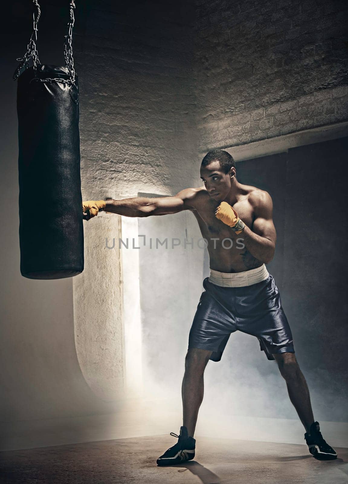 Hand of boxer and punching bag over black background. Strength, attack and motion concept. Fit african american model in movement. Afro muscular athlete in sport uniform. Sporty man during boxing exercises
