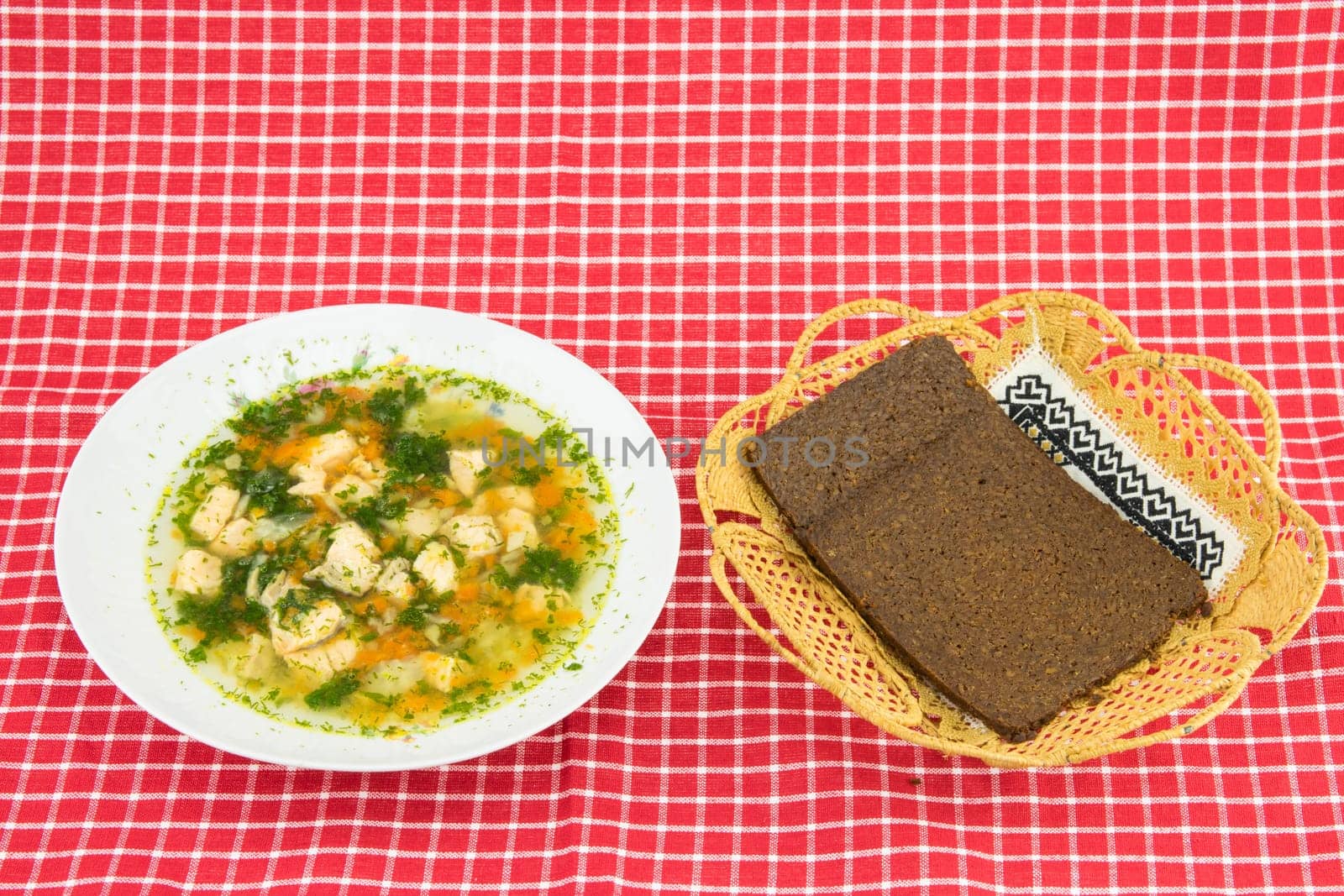 Healthy Fish soup salmon and whole grain bread in basket on red white checkered tablecloth. Health concept. Top view.