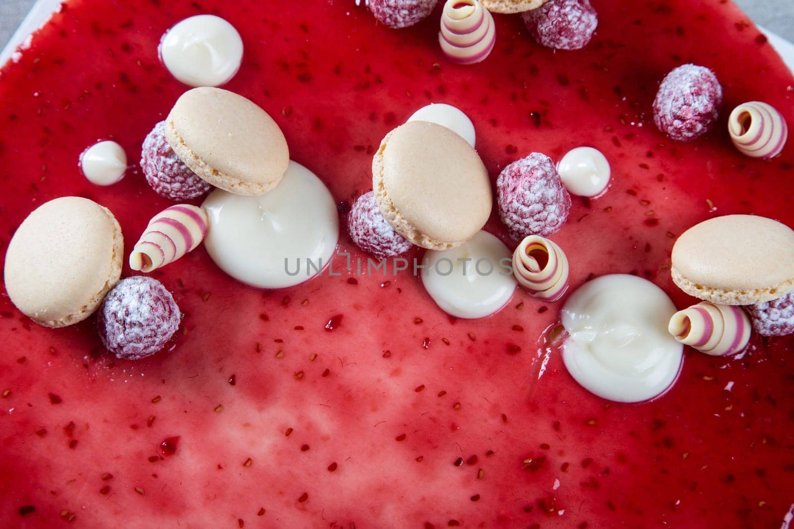 Decoration with raspberries, chocolates and biscuits on a cake