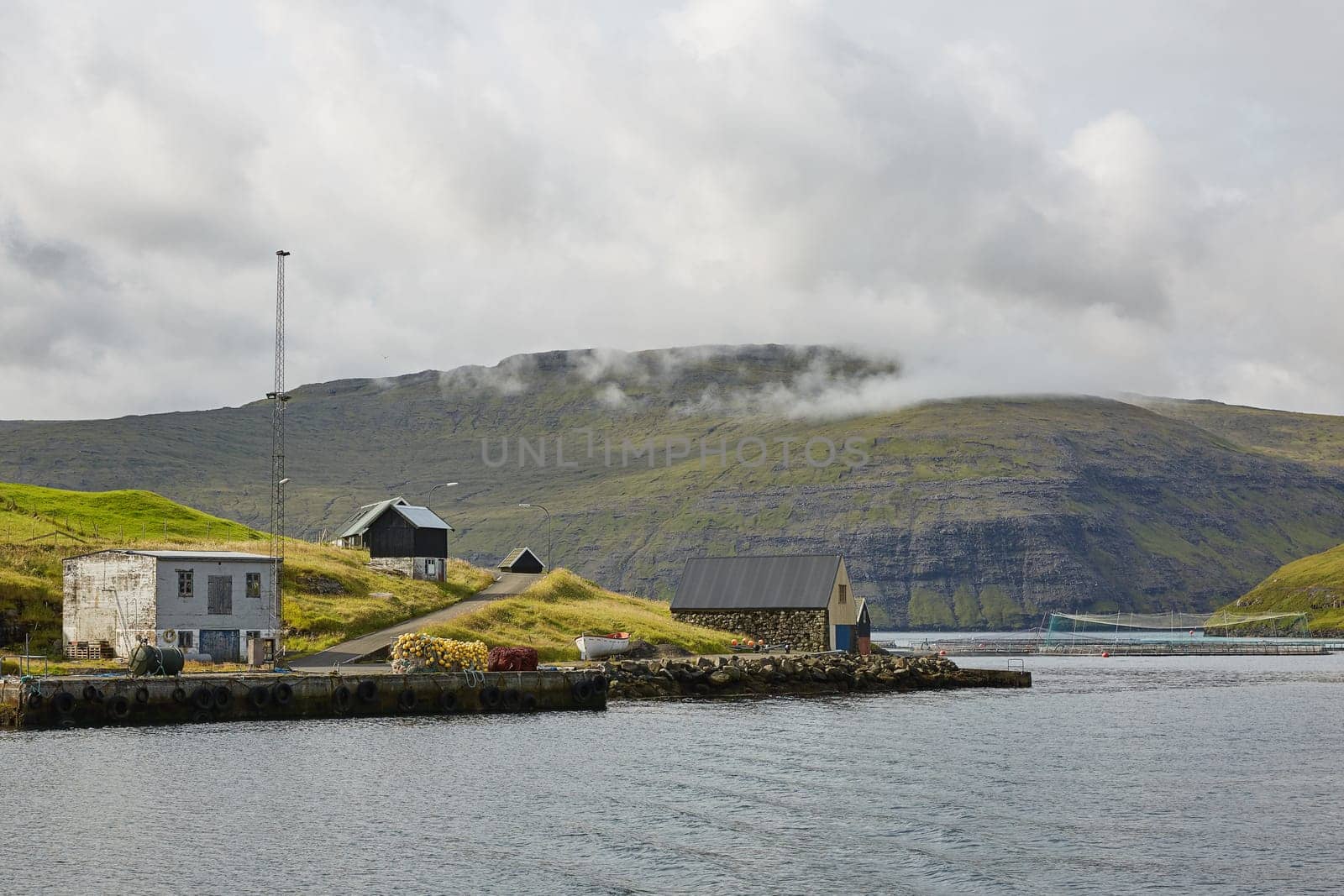 Village in wild and beautiful coastal landscape of Faroe Islands, Denmark.