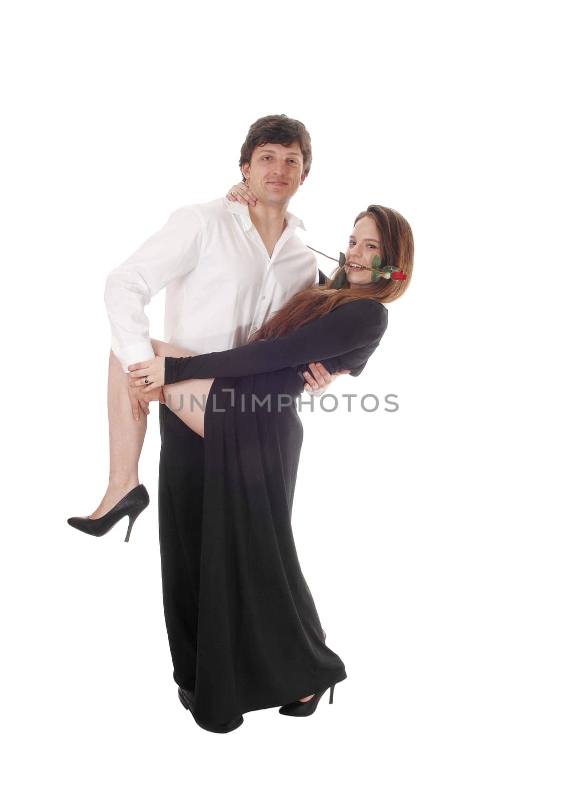 A gorgeous young couple, she in a long black dress, dancing, he holding.her leg up, isolated for white background.