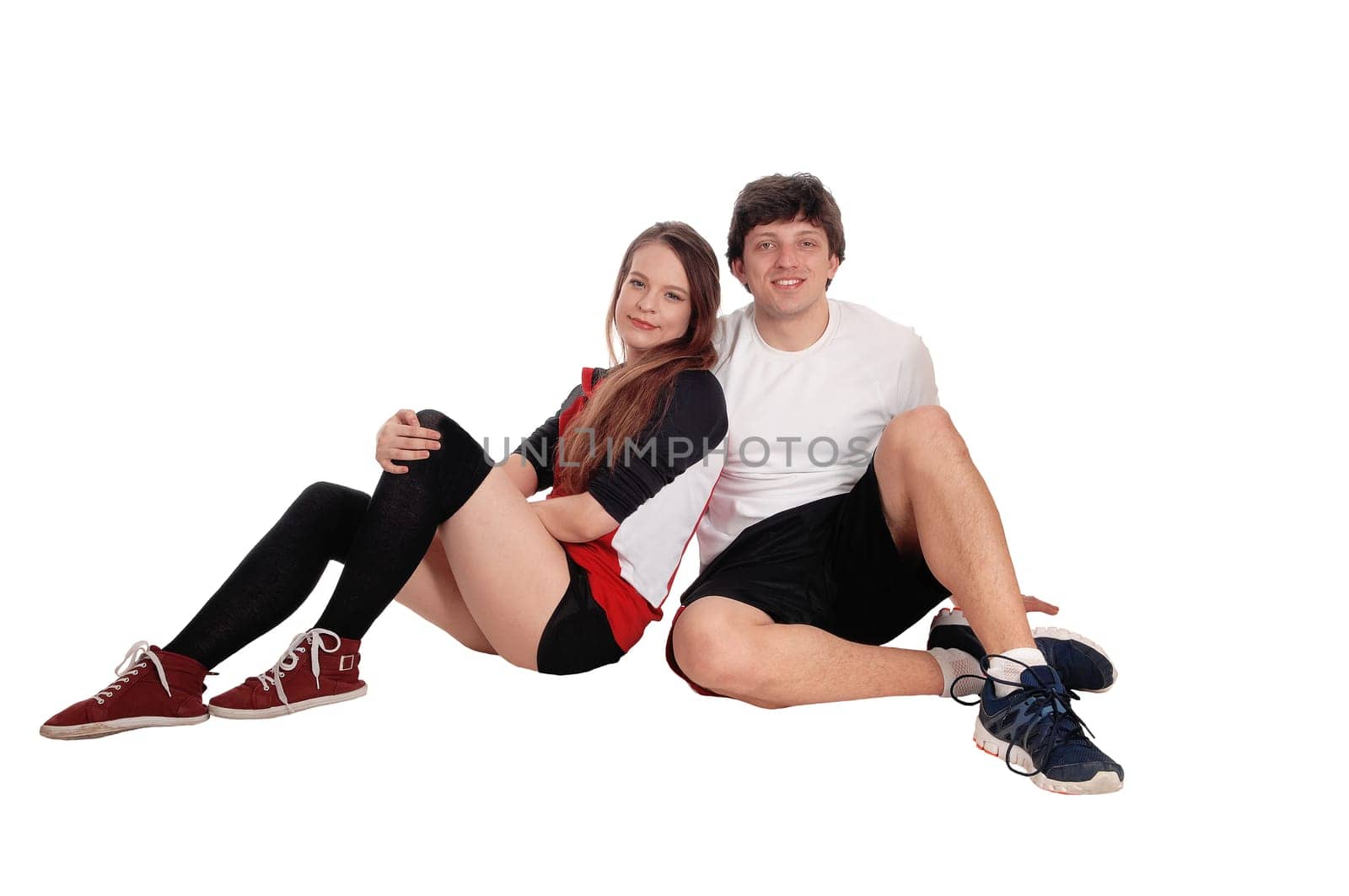 A beautiful young couple sitting on the floor in sports attire relaxing.after exercising, isolated for white background.