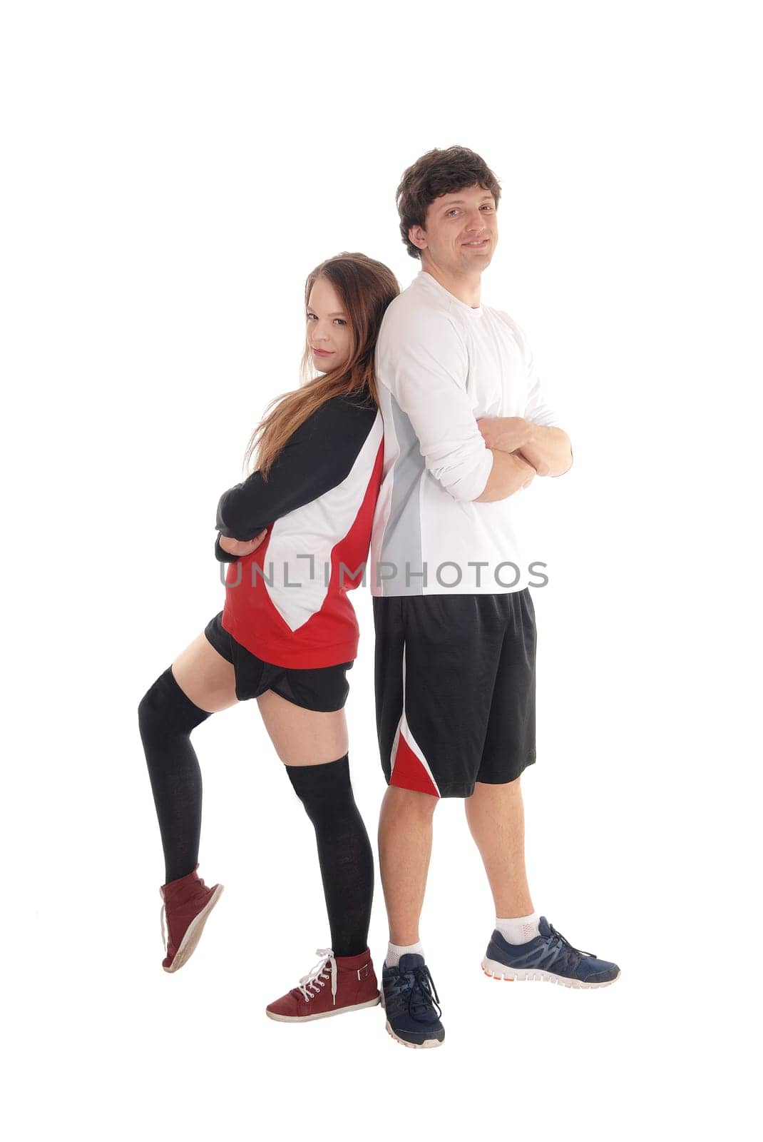 A lovely young couple in there twenties standing in sports attire back.to back with there arms crossed, isolated for white background.