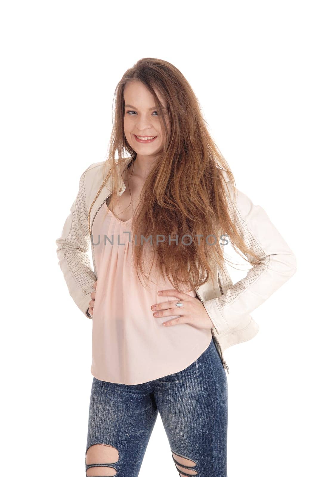 A gorgeous young woman standing with long brunette hair and a.ripped jeans, smiling, isolated for white background.