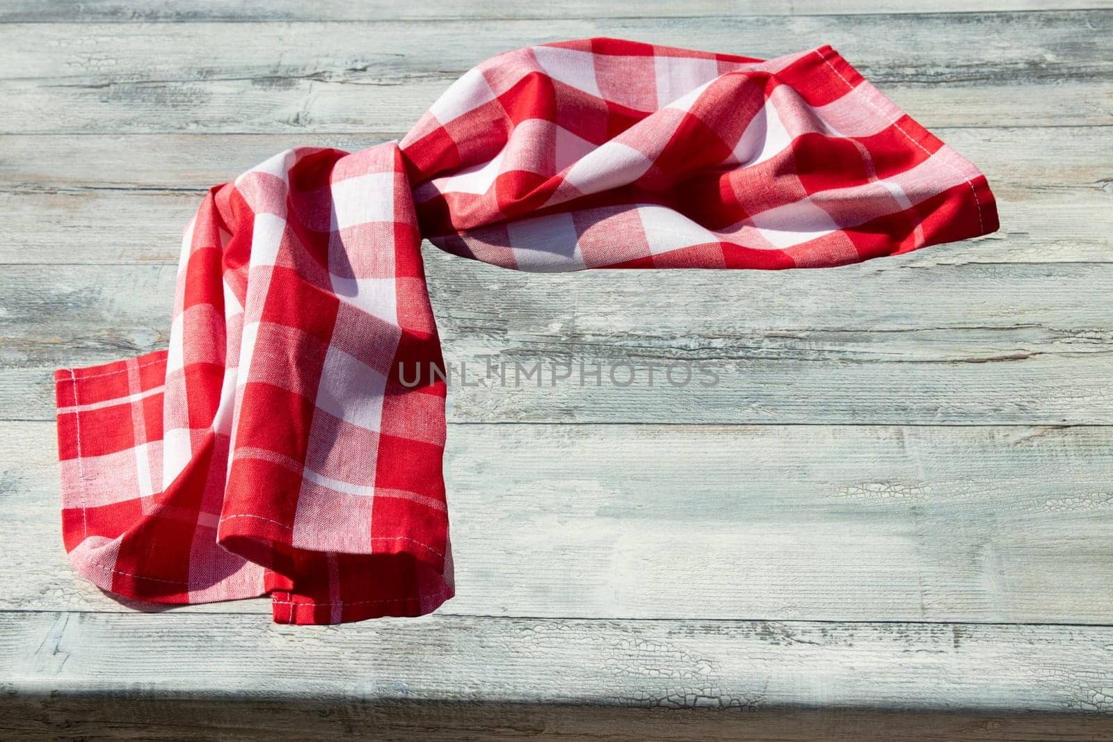 Red white checkered cloth on bright rustic wooden table. Template for food recipe, restaurant or store. Top view with copy space.