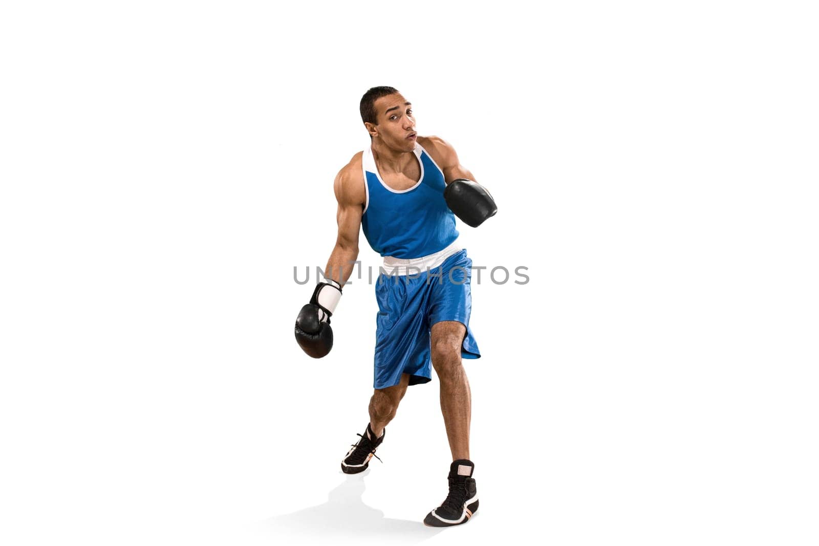 Sporty man during boxing exercises. Photo of boxer on isolated on white background. Strength, attack and motion concept. Fit african american model in movement. Afro muscular athlete in sport uniform