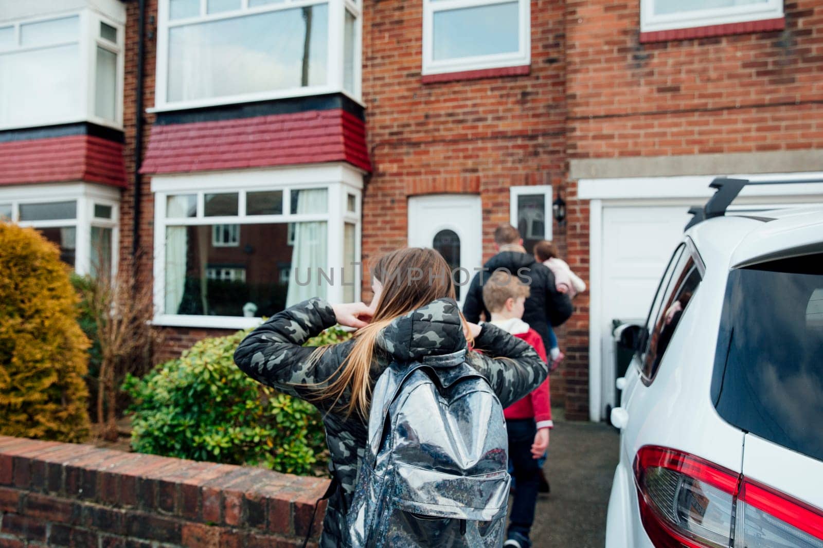 Mature man and his children have arrived home after picking up his eldest daughter from school.