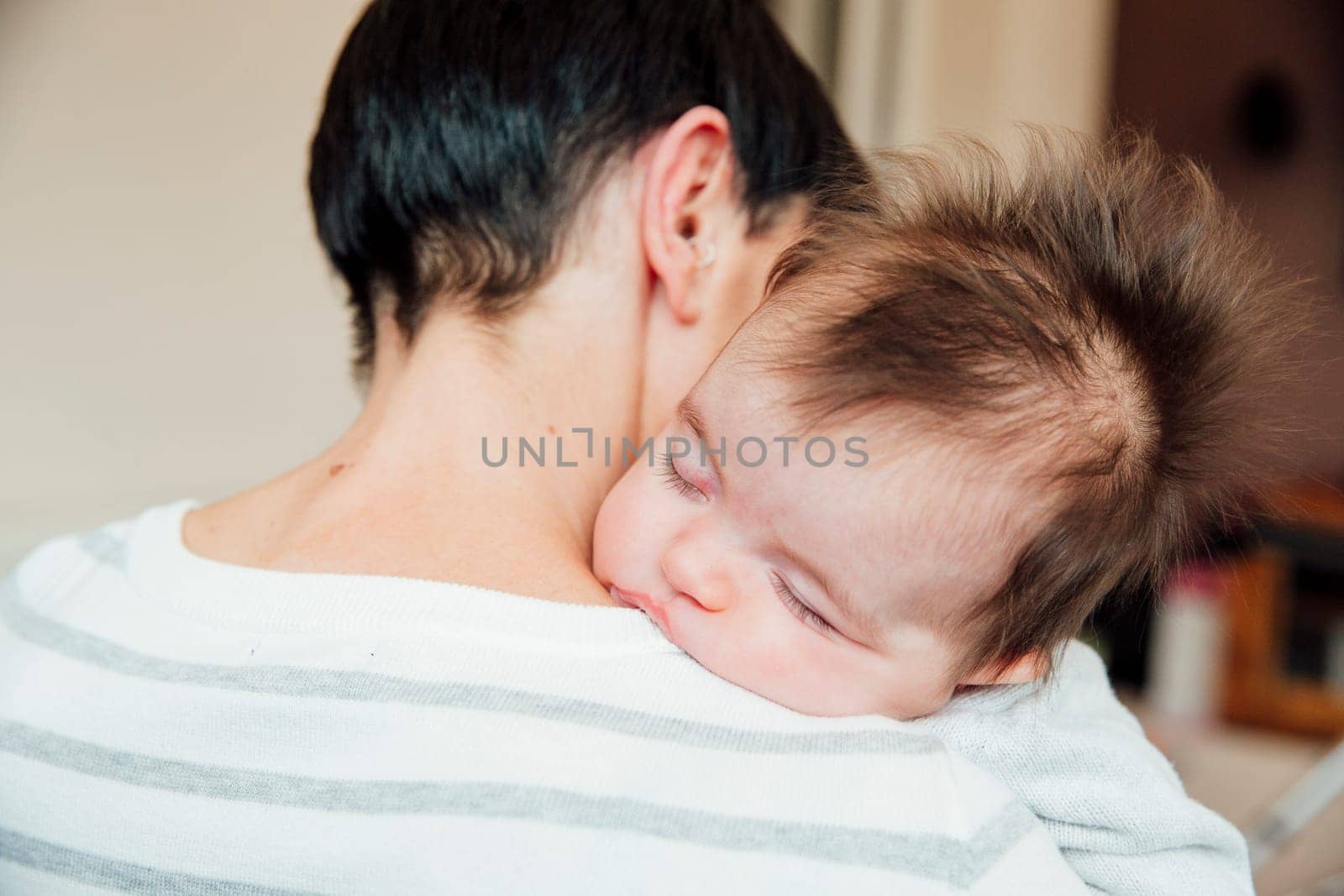 2 month old baby is sleeping over her mother's shoulder.