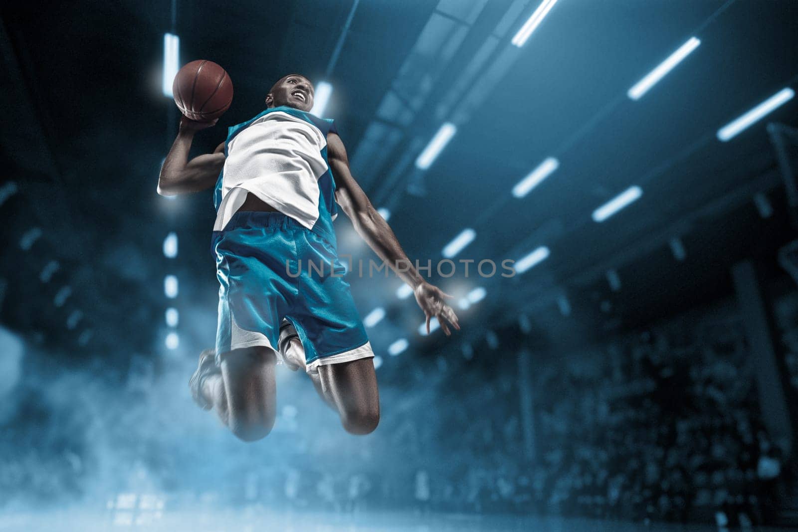 Basketball player in motion or movement on big professional arena during the game. Player making slam dunk. unbranded uniform. attack and decisive blow concept. professorial afro american athlete
