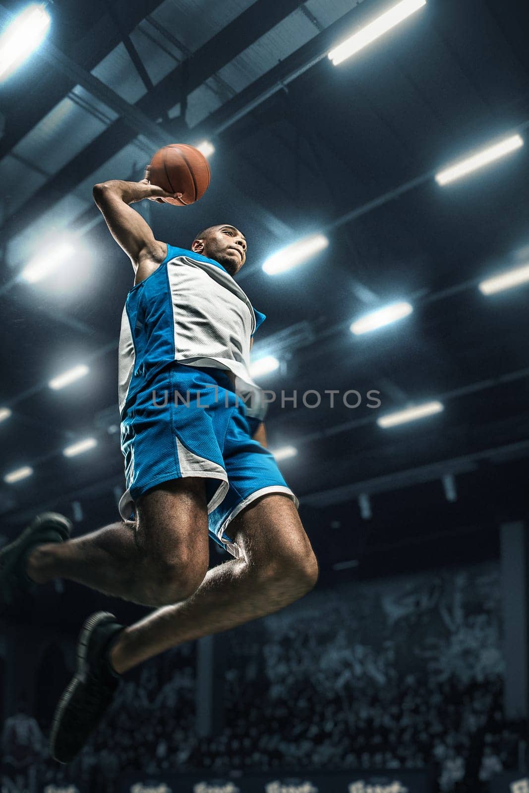 Basketball player in motion or movement on big professional arena during the game. Player making slam dunk. unbranded uniform. attack and decisive blow concept. professorial afro american athlete