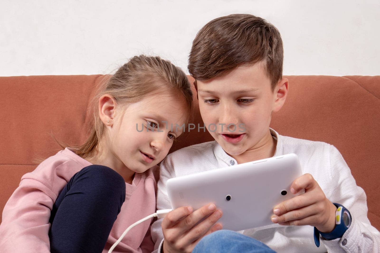 Girl and boy, sister and brother playing together with digital tablet