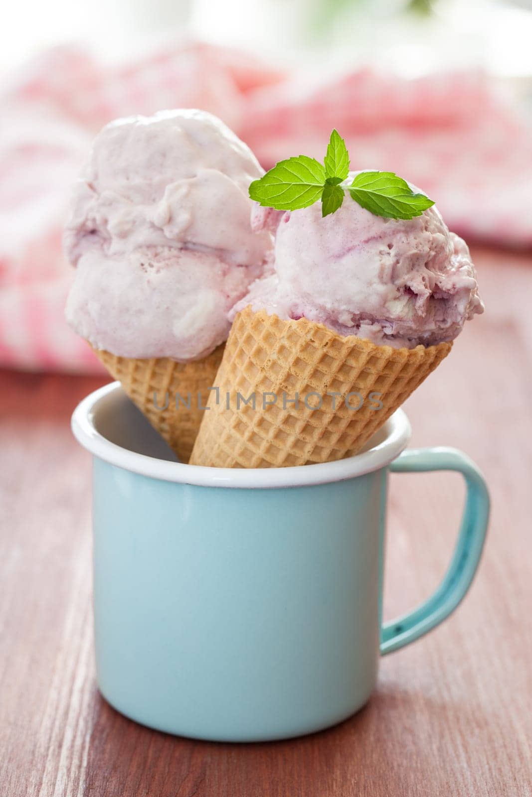 Cream cherry ice cream in waffle cloths in blue cup