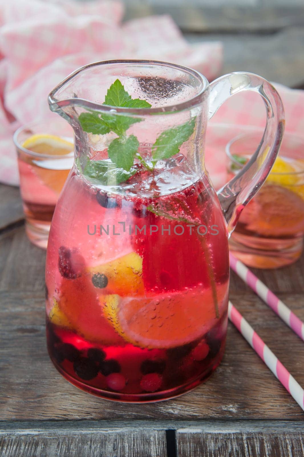 Small jug with colorful lemonade with lemon and mint