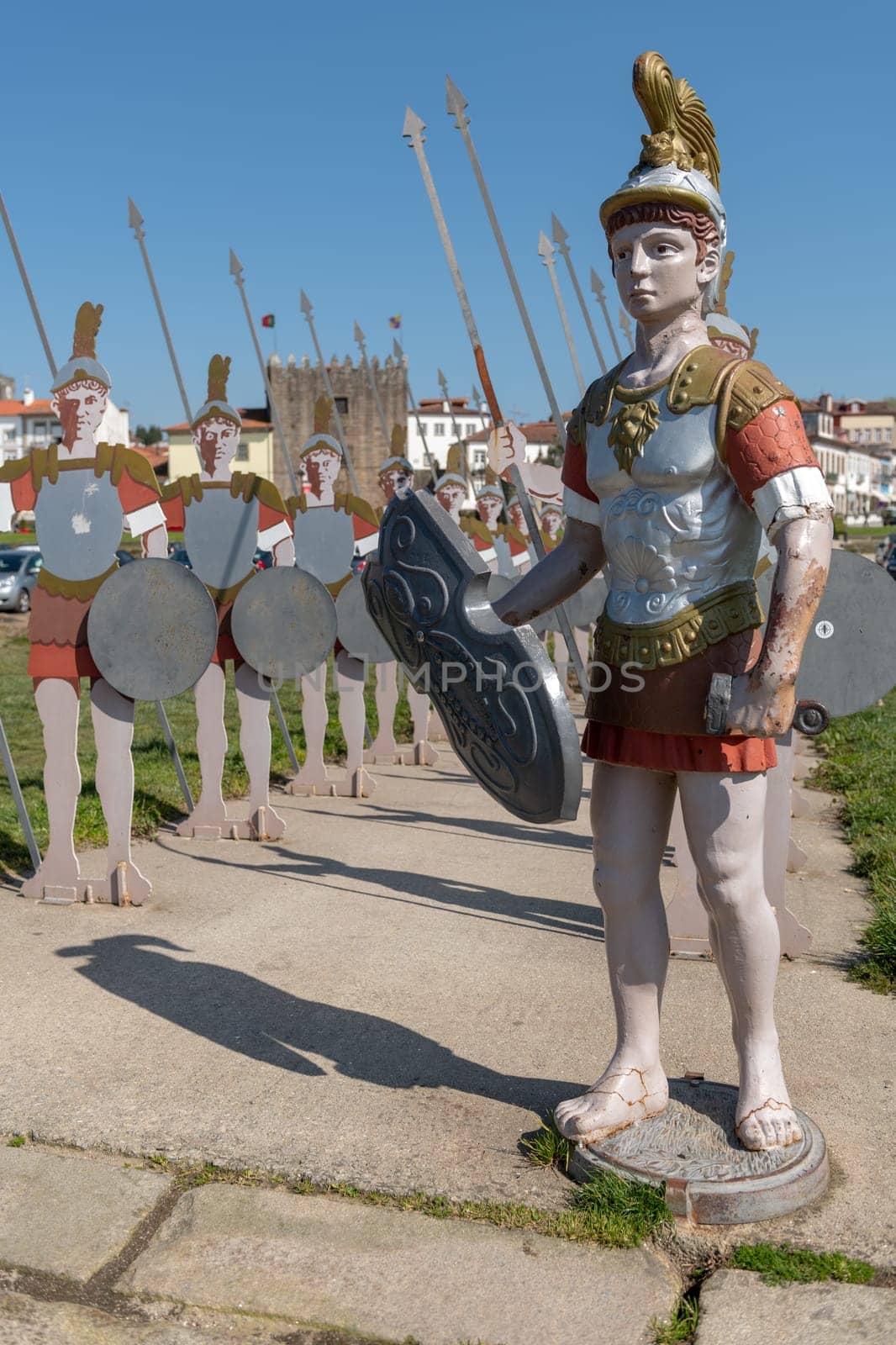 PONTE DE LIMA, PORTUGAL - CIRCA APRIL 2018: Statues of roman soldiers near Lima River at Ponte de Lima with Medieval Tower of the Old Jail on the background.
