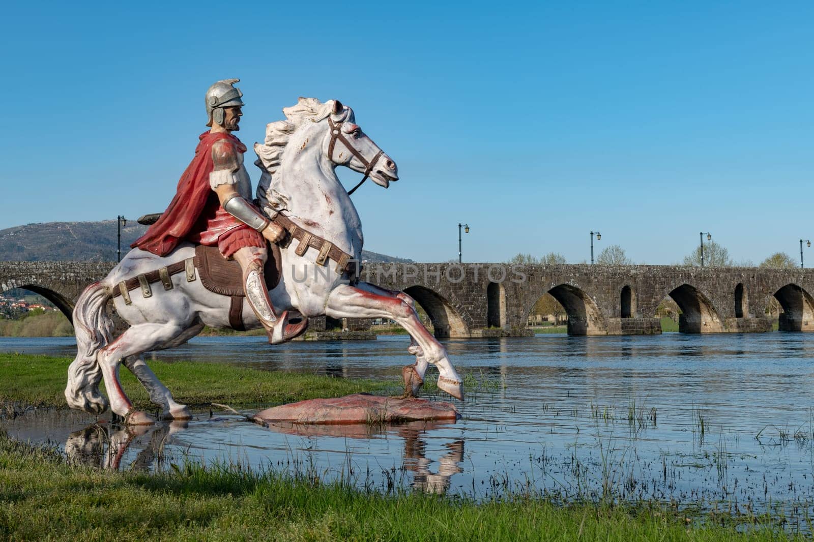 PONTE DE LIMA, PORTUGAL - CIRCA APRIL 2018: Statue of Roman soldier in front of the Roman bridge crossing the Rio Lima in Portugal.