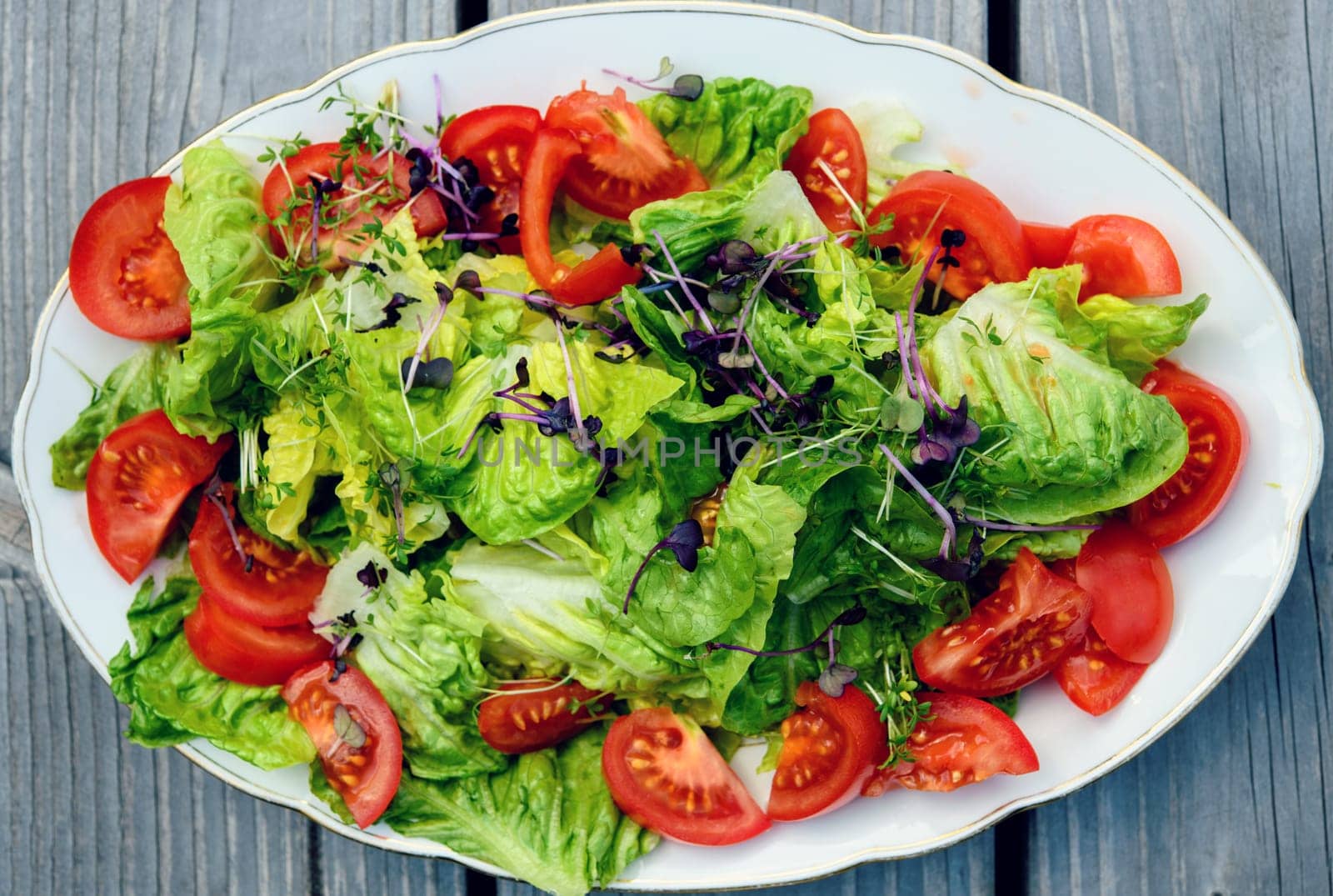 mixed summer salad on plate and wooden ground