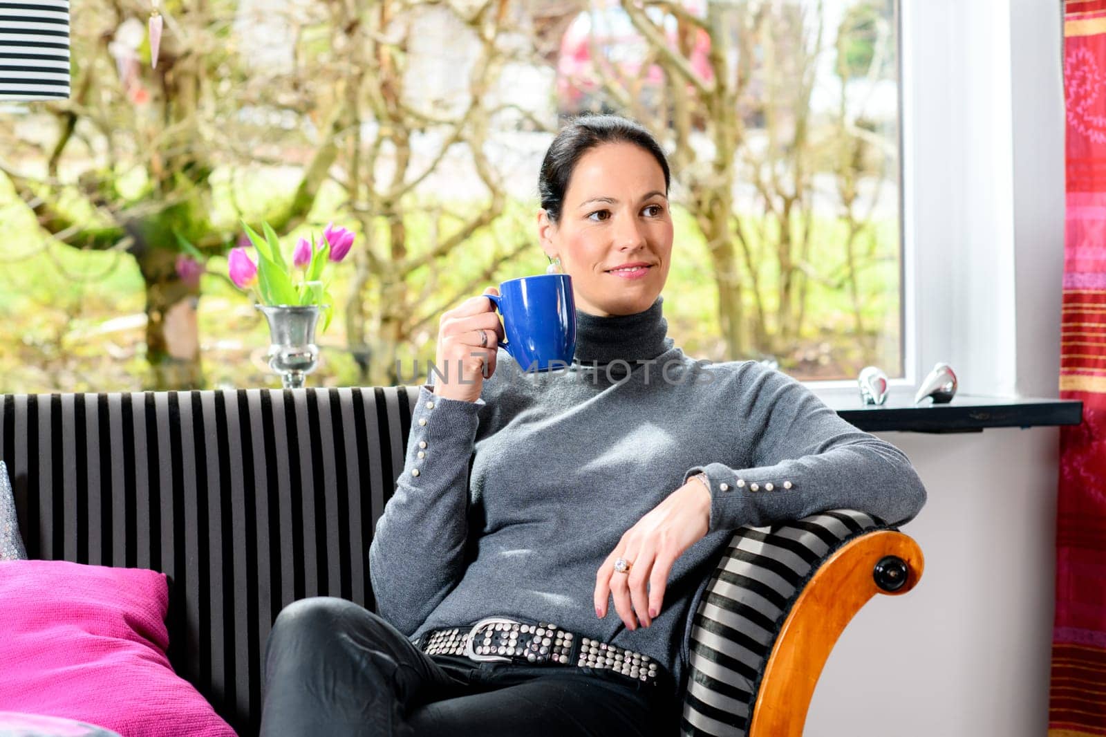 young dark haired woman at home with cup of coffeee relaxing