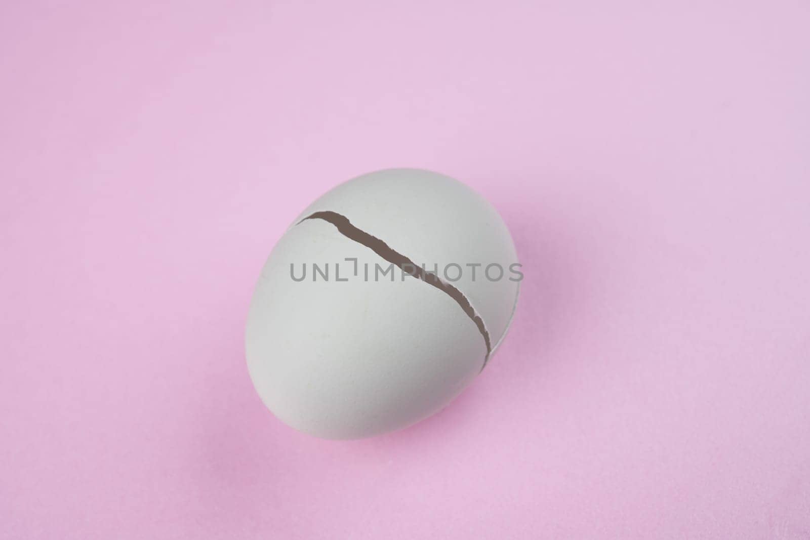 broken egg with crack on pink ground