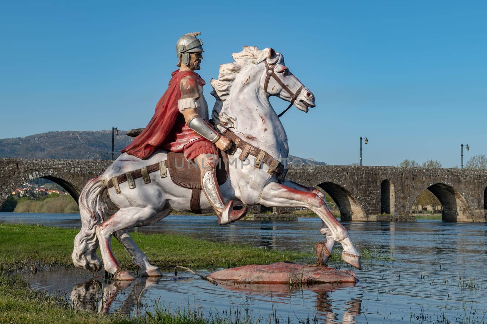PONTE DE LIMA, PORTUGAL - CIRCA APRIL 2018: Statue of Roman soldier in front of the Roman bridge crossing the Rio Lima in Portugal.