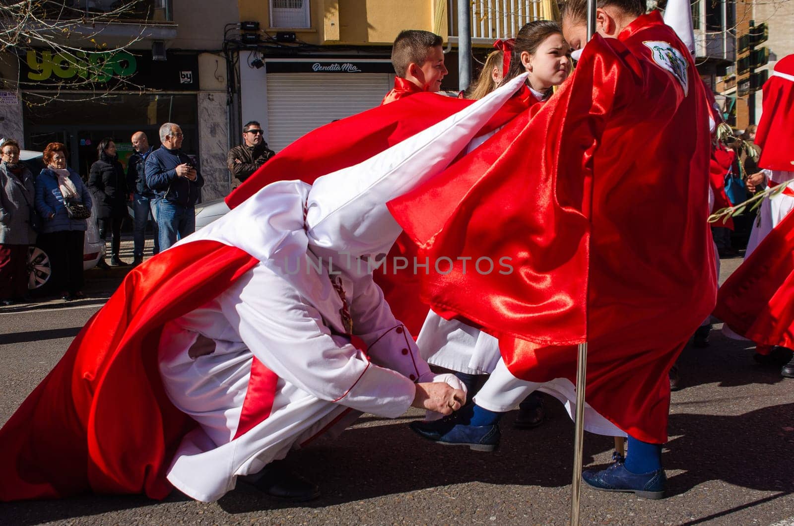Sunday 17 march 2018, Badajoz, Spain.   Nazarene tying shoe little boy in the street.