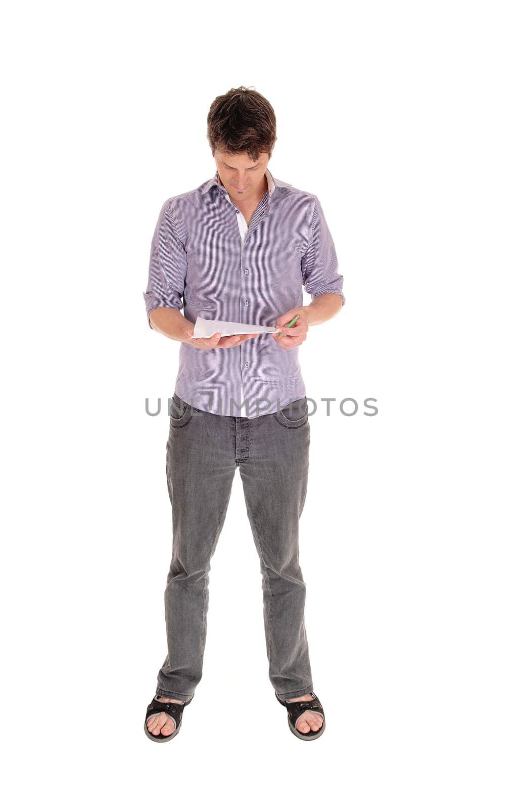 A handsome young Caucasian man standing in jeans and sandals .isolated for white background  and reading his papers.