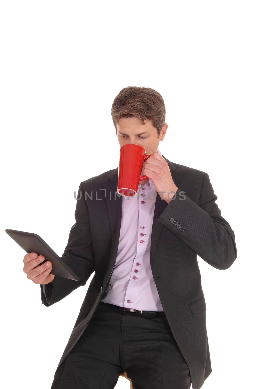 A working young businessman sitting with his tablet and a coffee mug.in his hands enjoying a brake, isolated for white background.