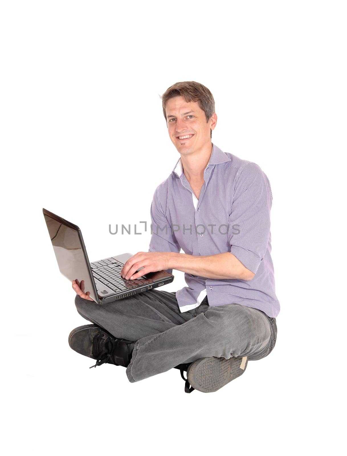 A handsome young business man in a checkered shirt and jeans sitting.on the floor and working, isolated for white background.