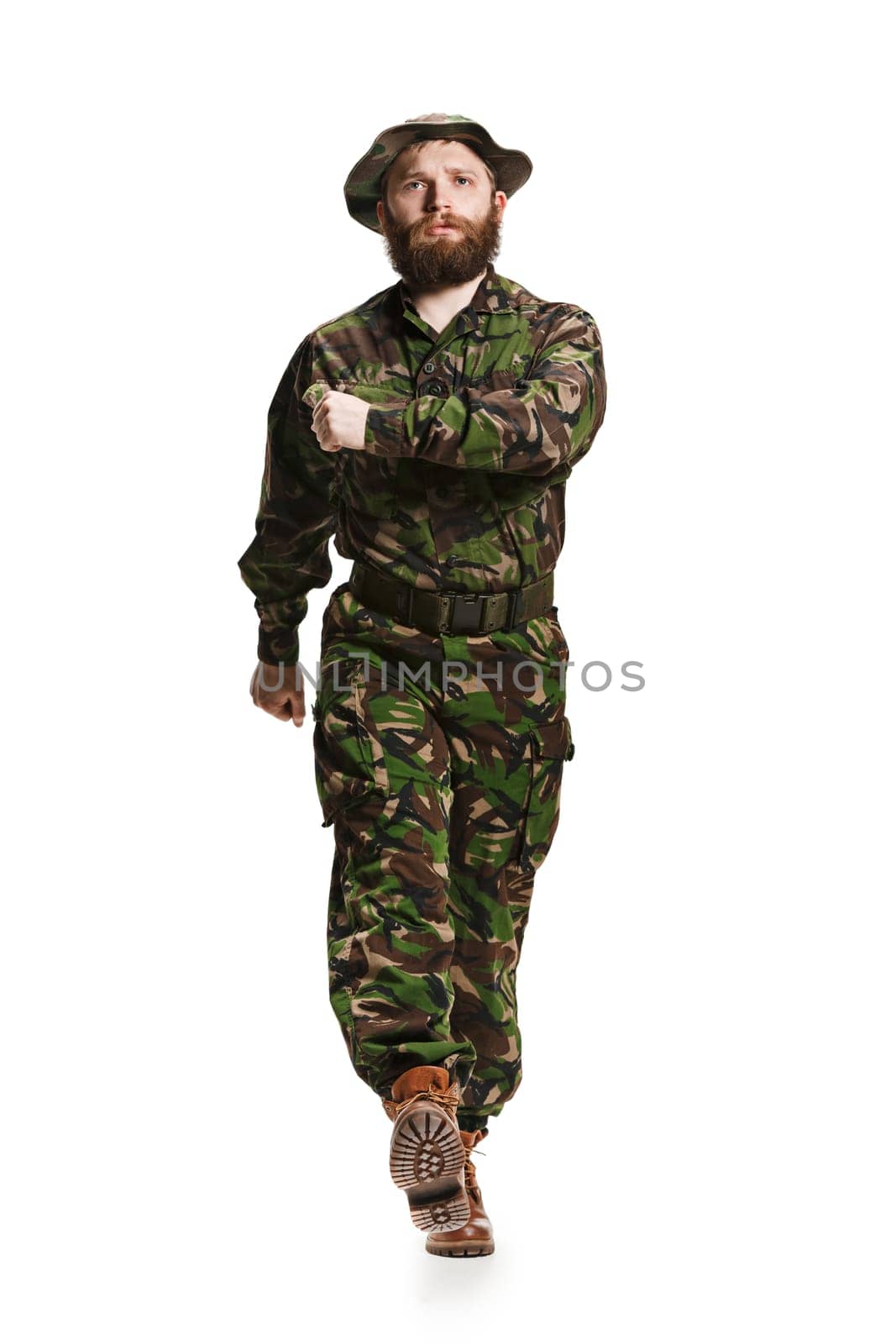 Young army soldier wearing camouflage uniform going isolated on white studio background in full-length. Young caucasian model. Military, soldier, army concept. Proffeshional concepts