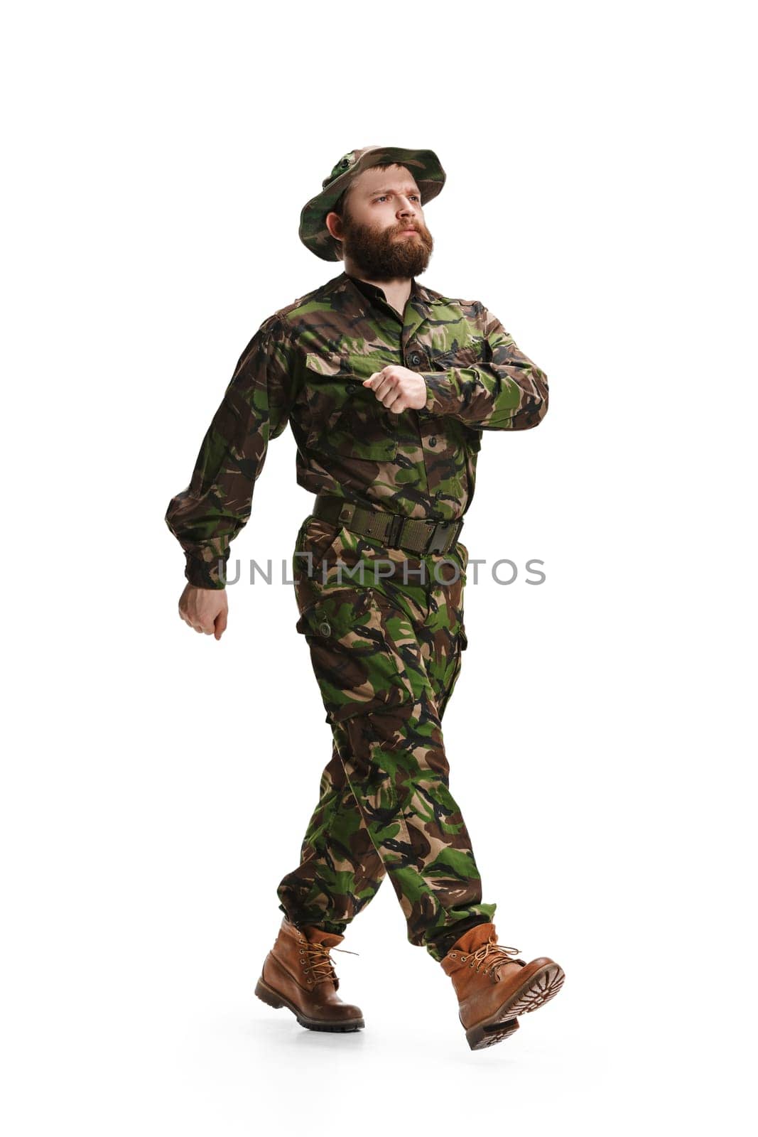 Young army soldier wearing camouflage uniform going isolated on white studio background in full-length. Young caucasian model. Military, soldier, army concept. Proffeshional concepts