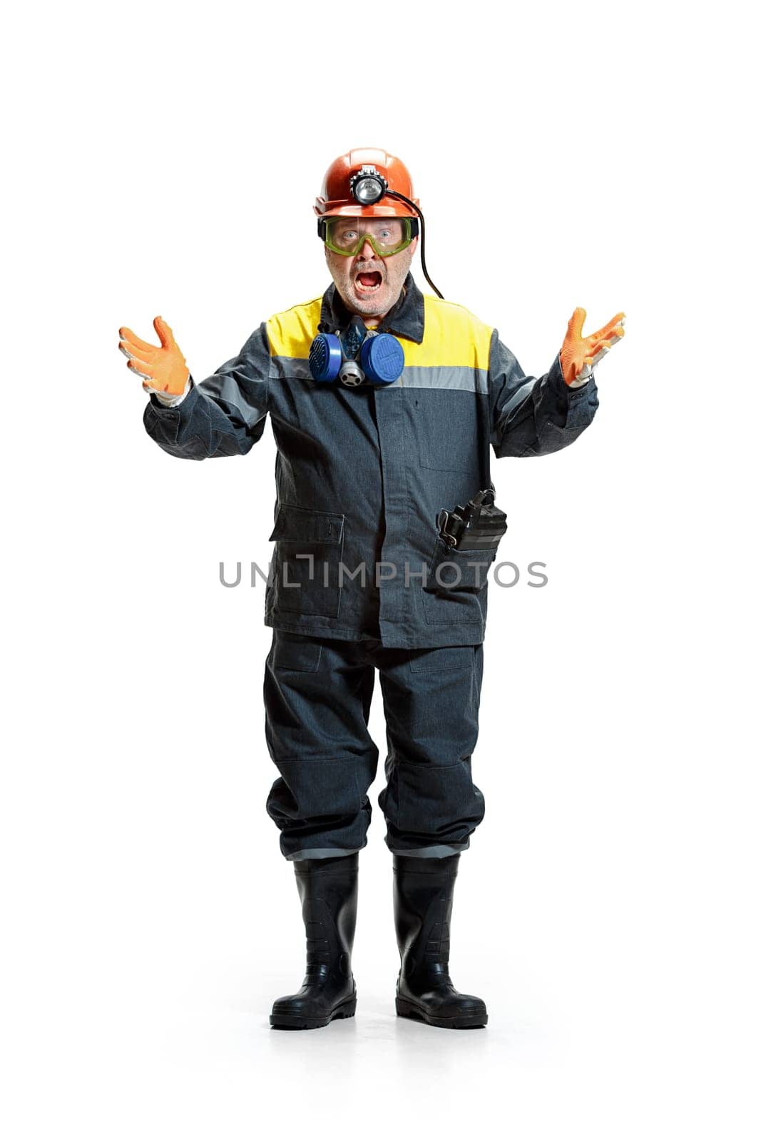 The studio shot of screaming senior bearded serious male miner in professional helmet standing at the camera isolated on a white studio background. Woker and industry concept. Mature caucasian model
