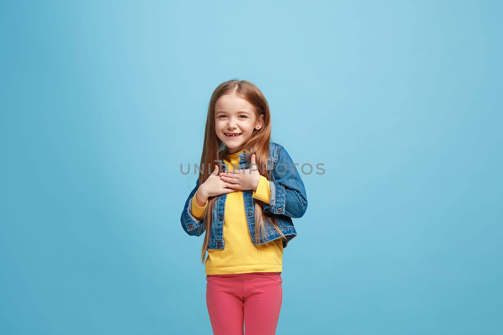 Happy teen girl standing, smiling isolated on trendy pink studio background. Beautiful female half-length portrait. Human emotions, facial expression concept.