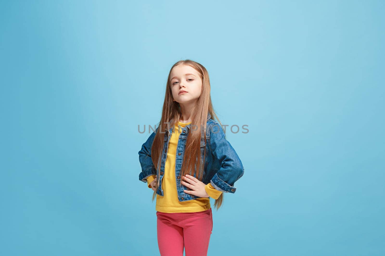 Serious doubtful, thoughtful teen girl remembering something. Young emotional woman. Human emotions, facial expression concept. Studio. Isolated on trendy blue. Front