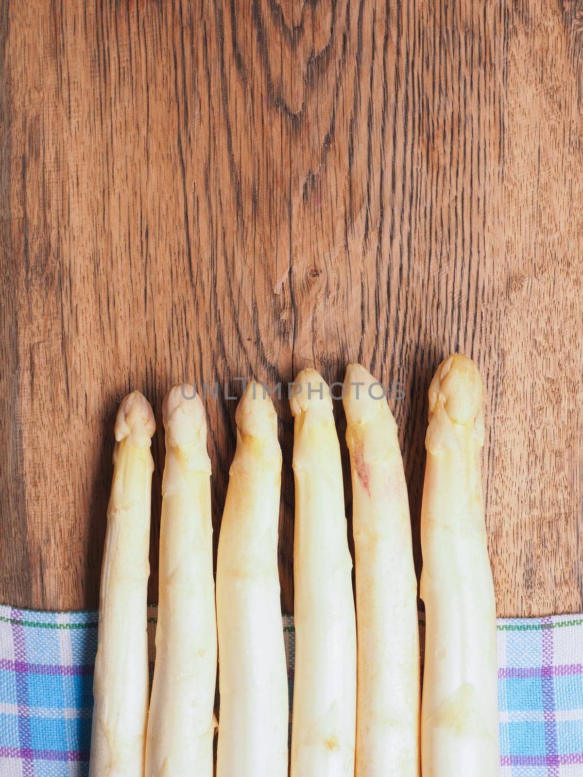 Raw organic white asparagus on a rustic wooden kitchen table, healthy or seasonal food