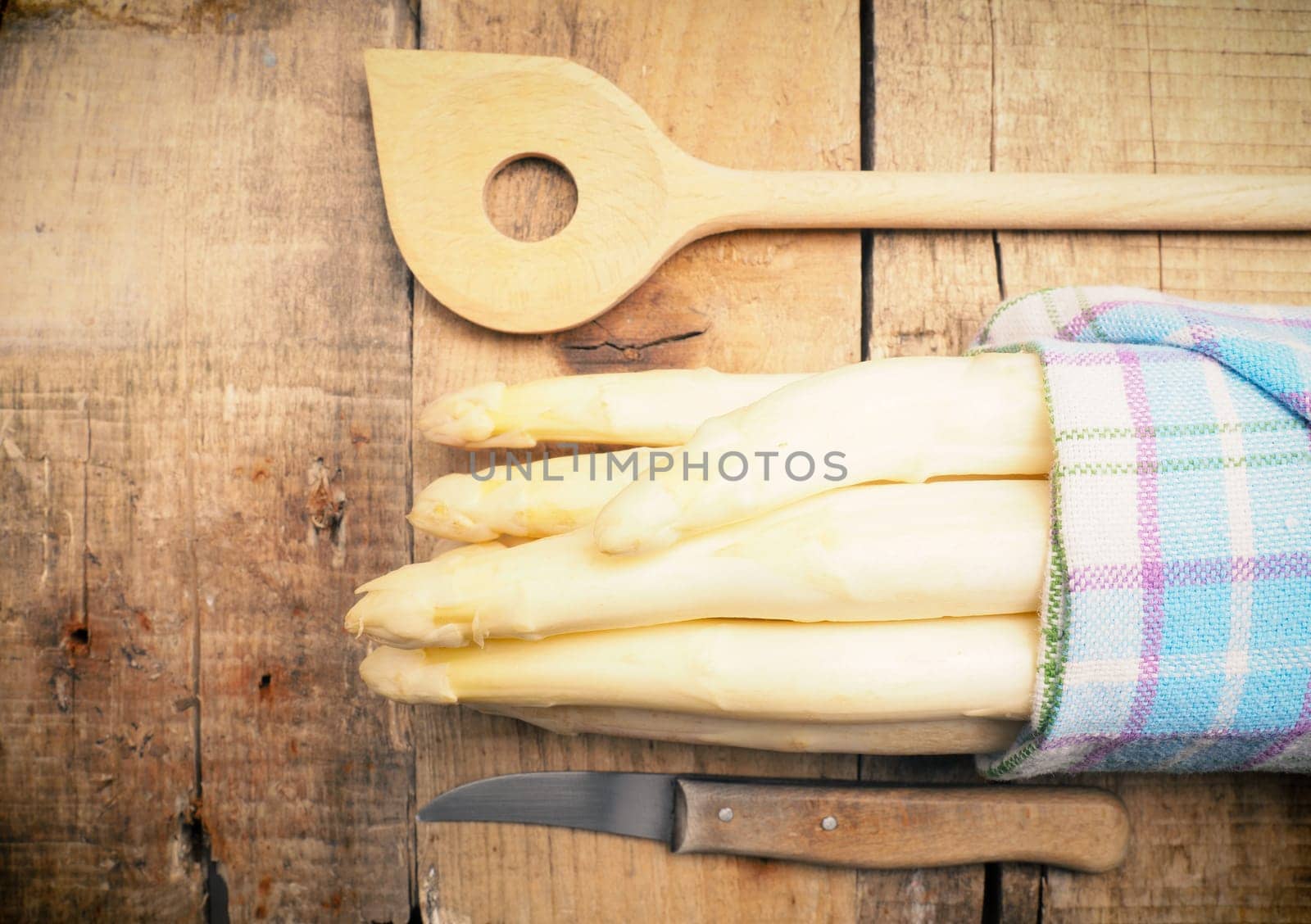 Raw organic white asparagus on a rustic wooden kitchen table, healthy or seasonal food