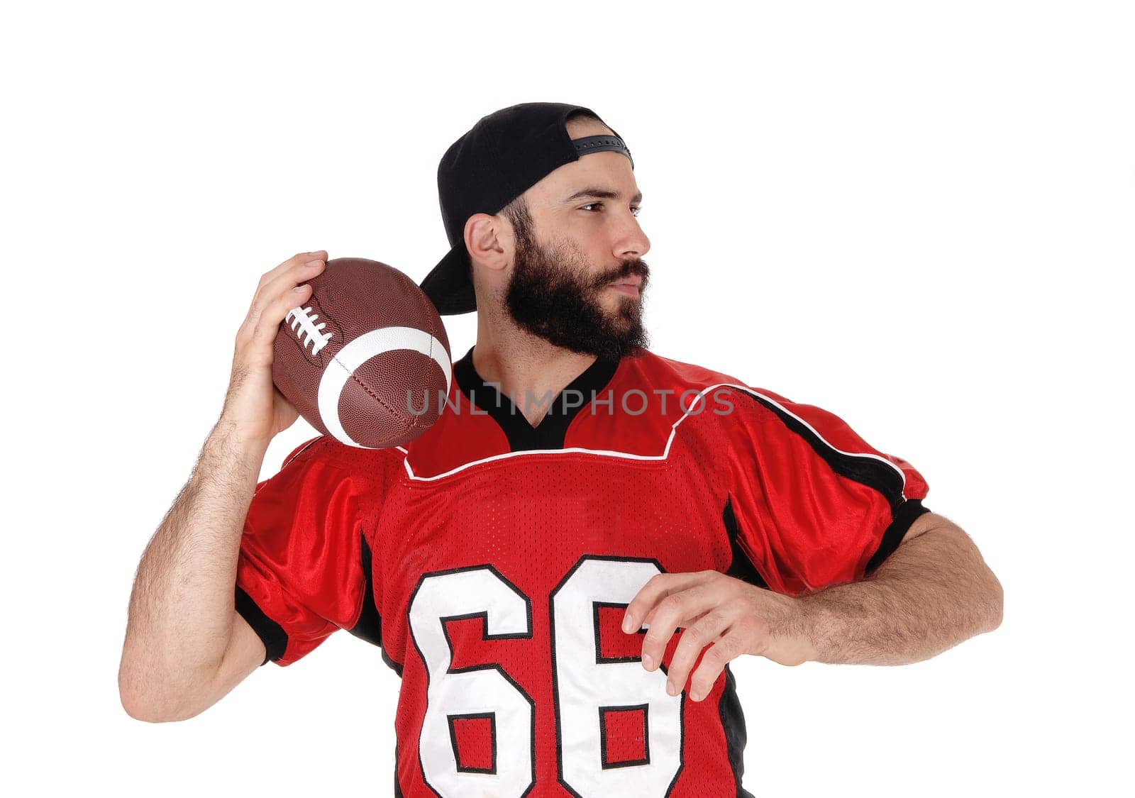 An American football player standing with his ball in his hand in a .close up image, with a beard and mustache, isolated over white.