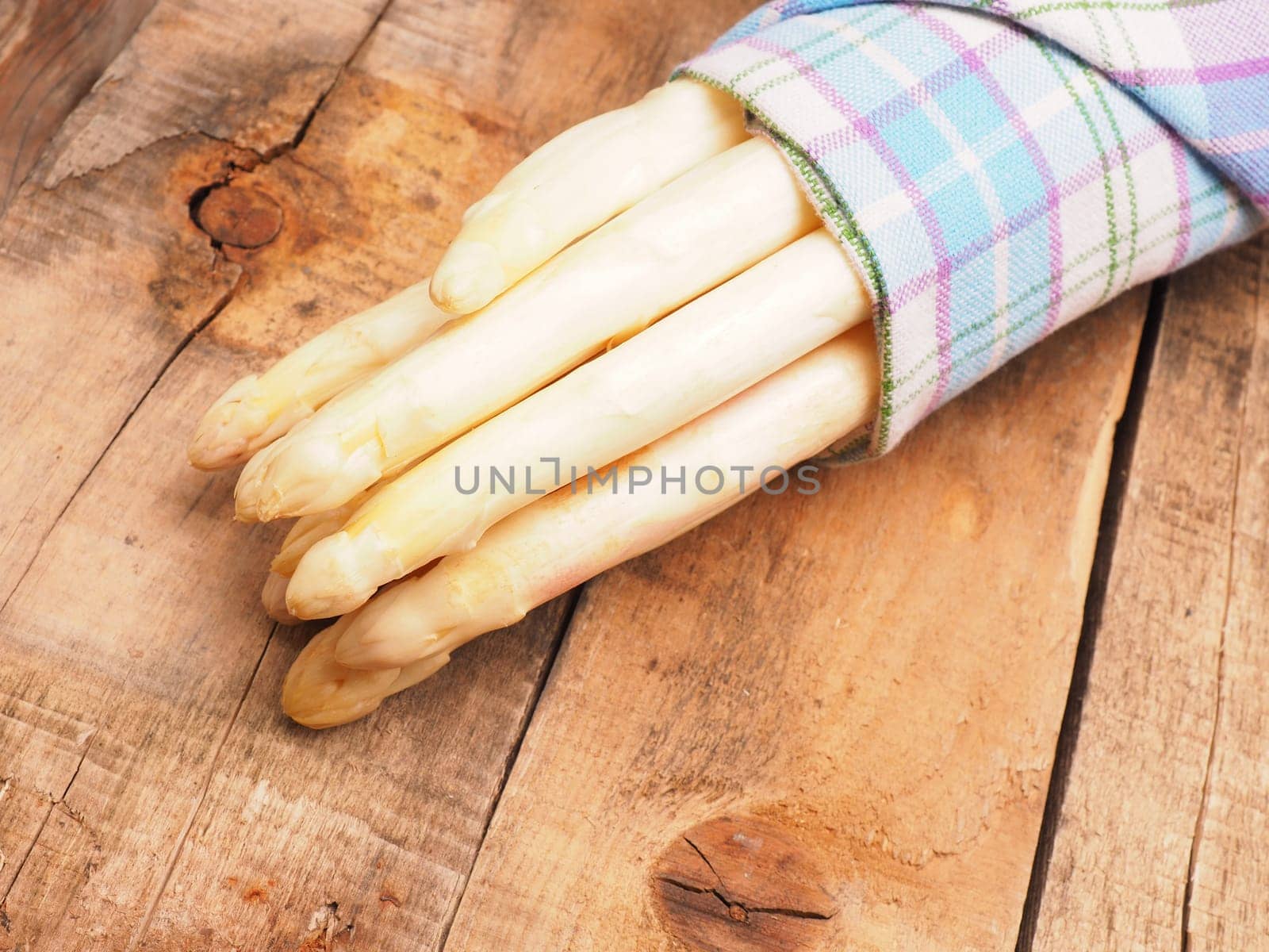 Raw organic white asparagus on a rustic wooden kitchen table, healthy or seasonal food