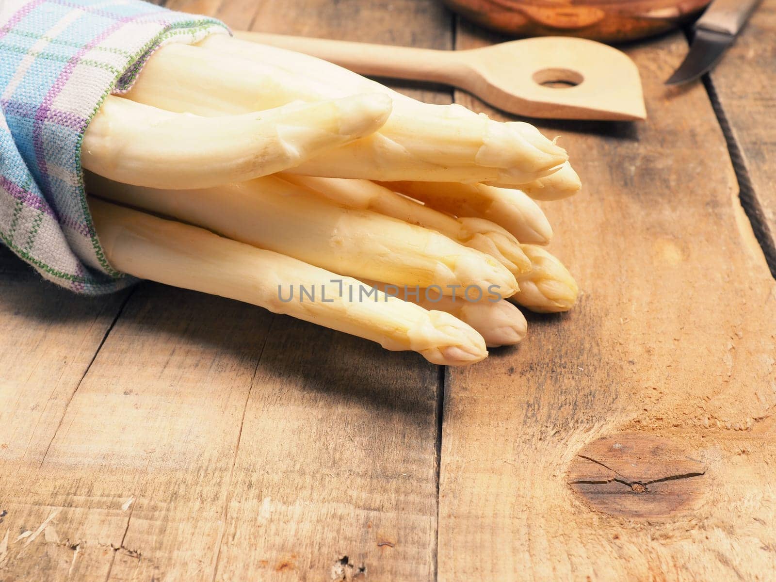Raw organic white asparagus on a rustic wooden kitchen table, healthy or seasonal food