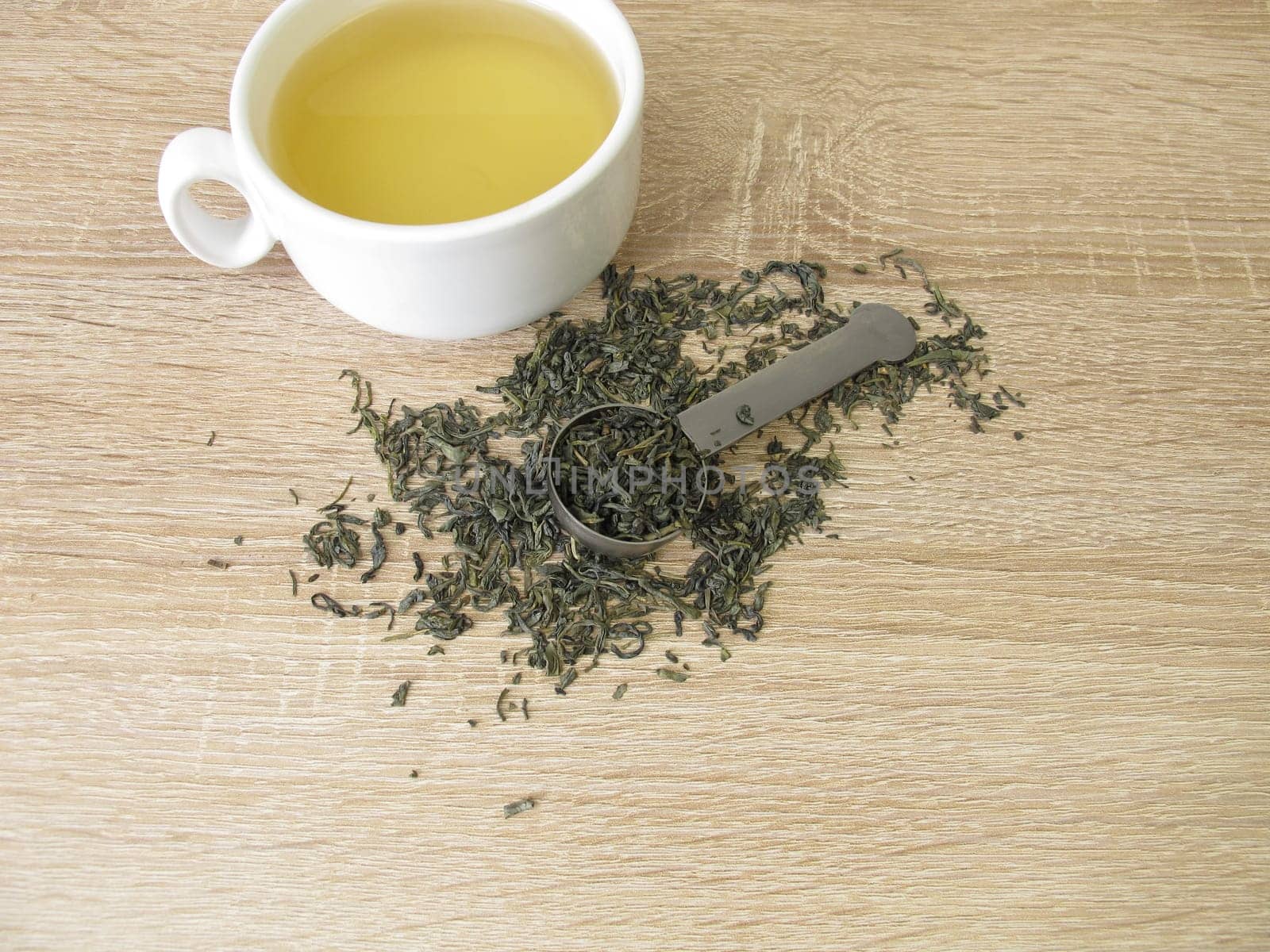 Green tea Chun Mee in tea measure and a cup of green tea