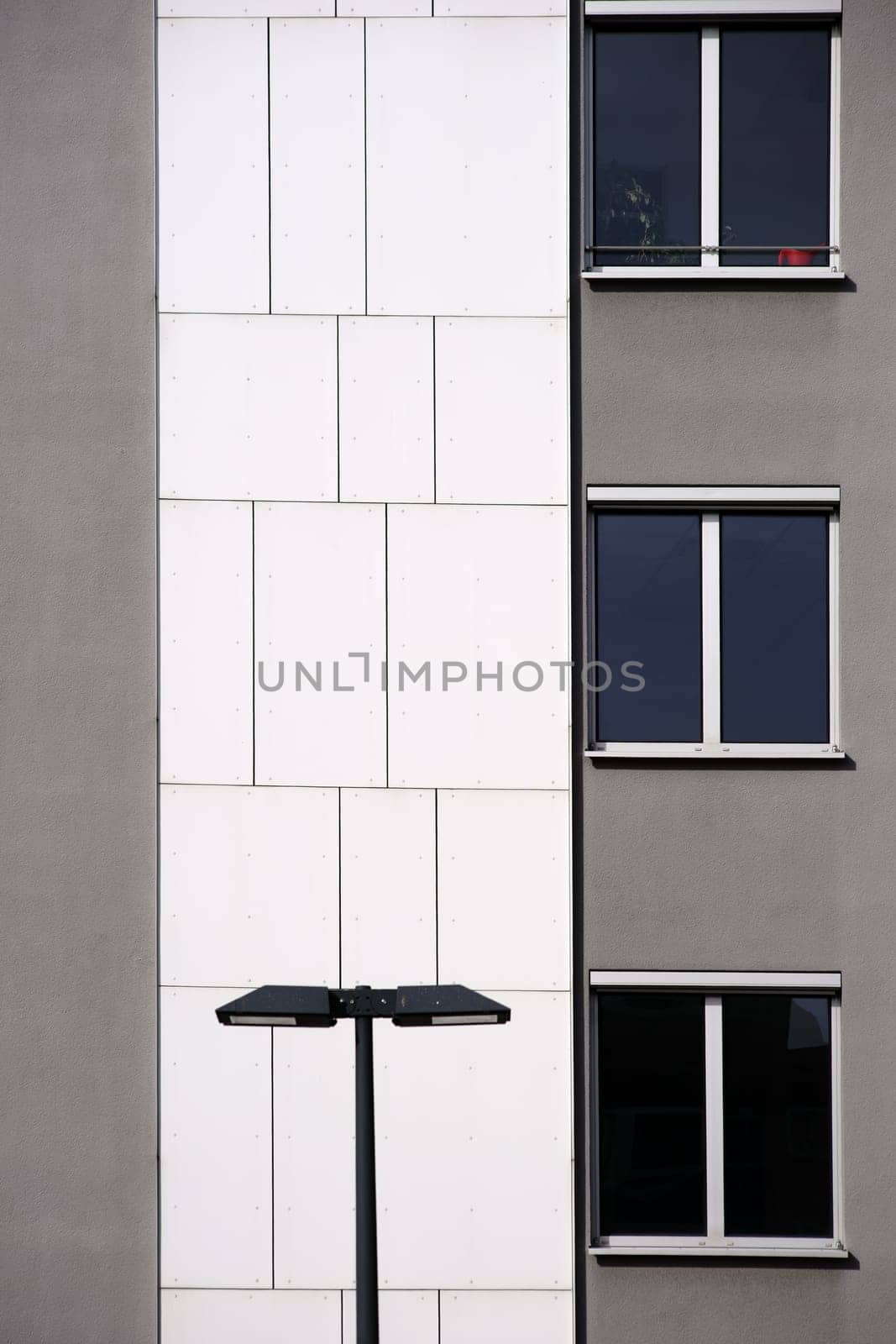 A lantern stands in front of a modern house façade with gray and white wall cladding.