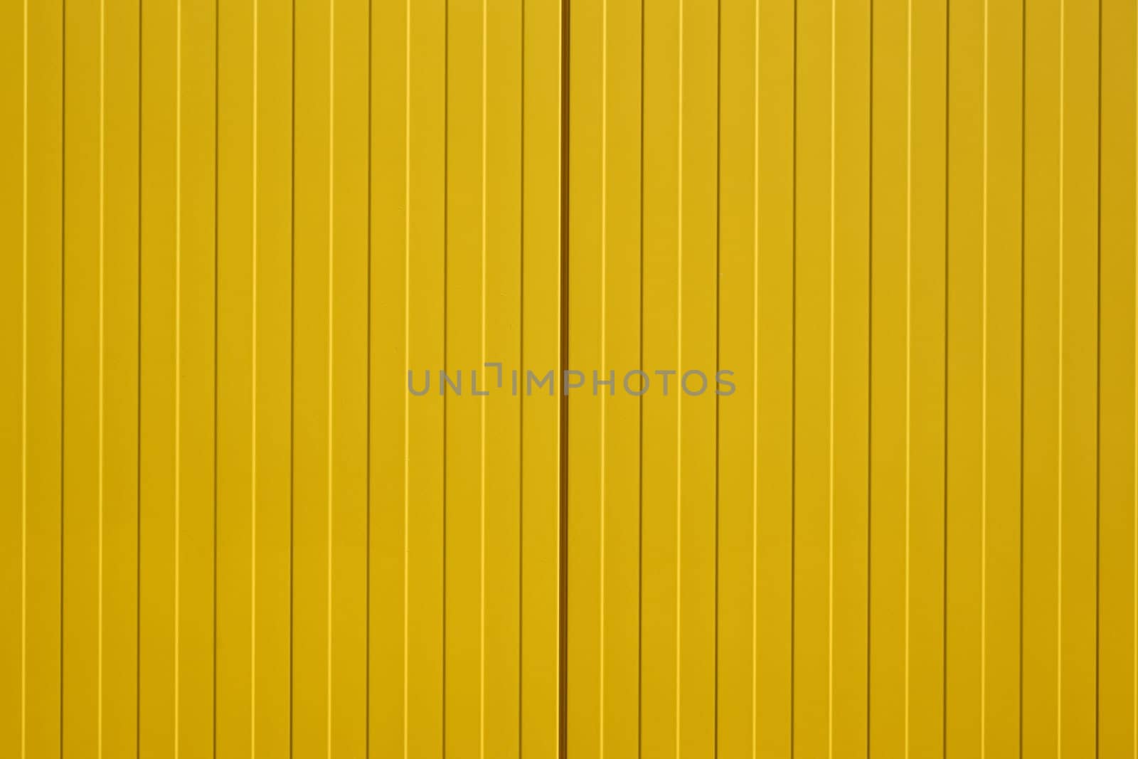 The close-up of a colorful and bright yellow corrugated iron wall of a shopping center.