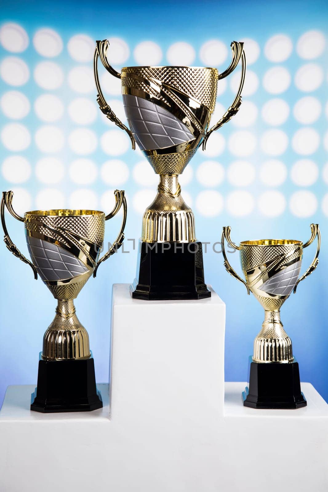 Cups of winners award on white podium, sport background