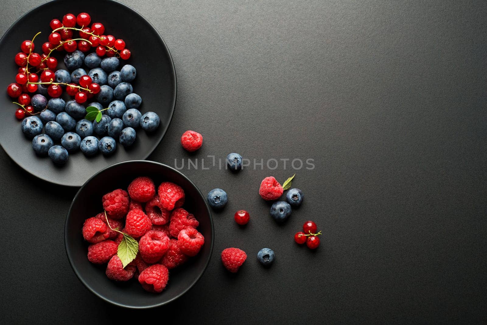 Mix of fresh berries in a bowl on black background