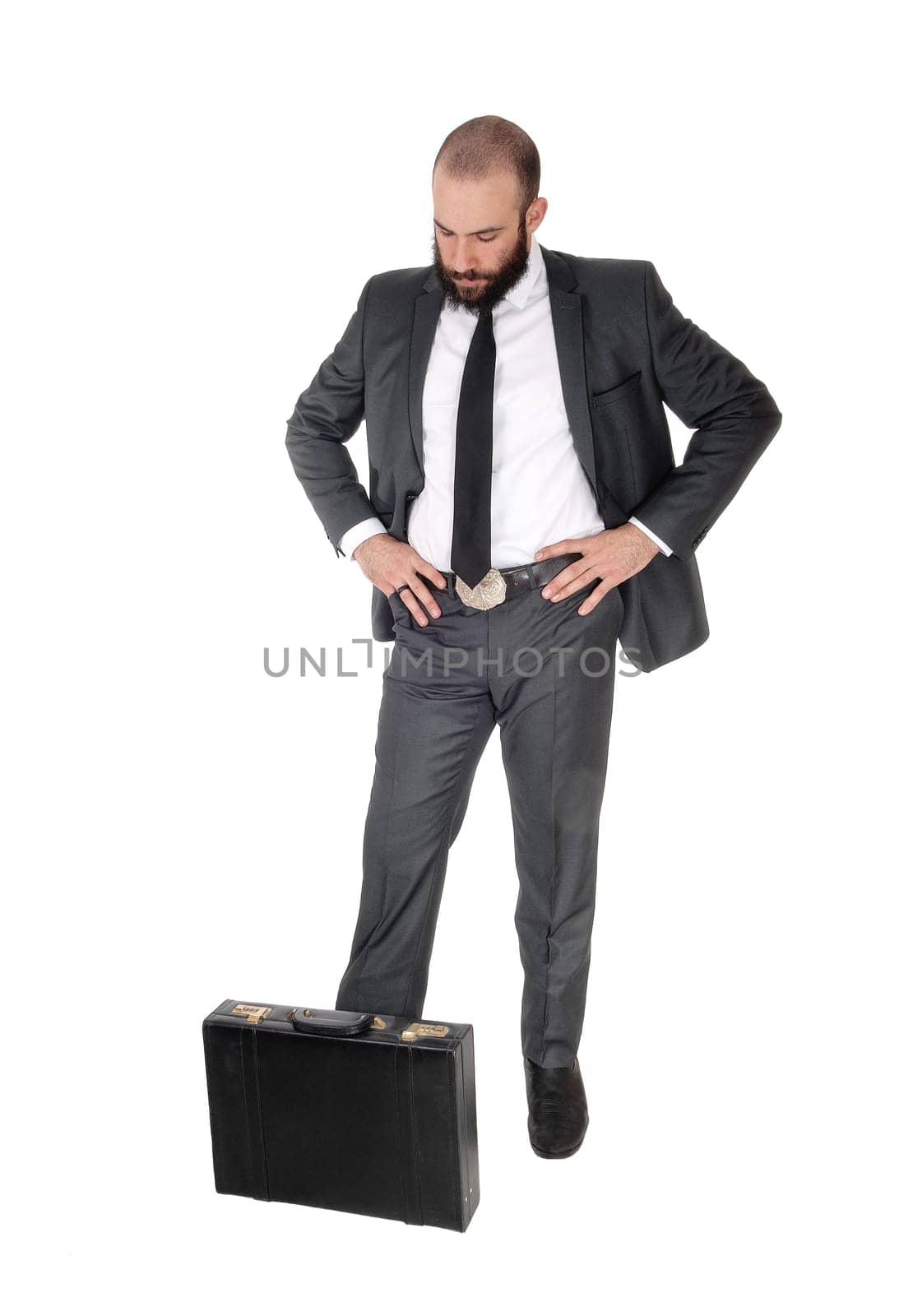 A young handsome business man standing, looking down man thinking.with his briefcase to his feet, isolated for white background.