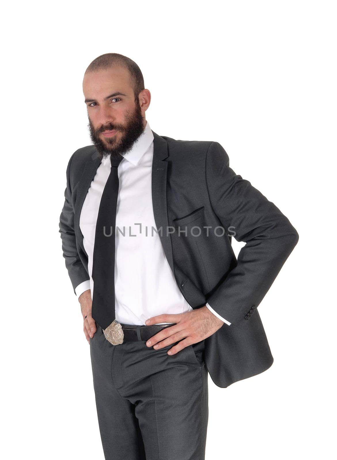 A handsome young businessman standing in a suit and tie with his.hands on his hips, with a beard, isolated for white background.