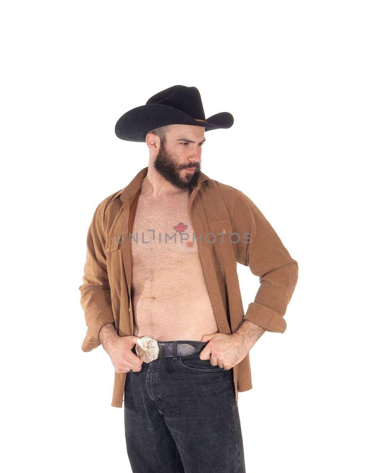 A close up image of a young man in a open brown shirt wearing a.cowboy hat and black jeans, isolated for white background.